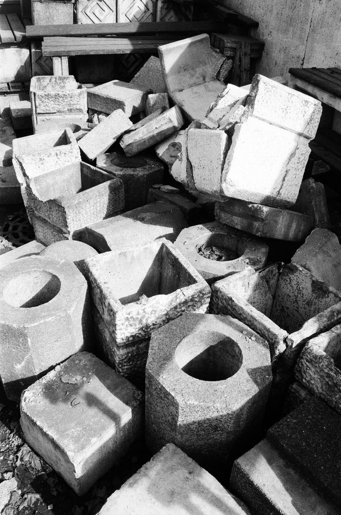 A monochrome image of various concrete blocks piled haphazardly outdoors.